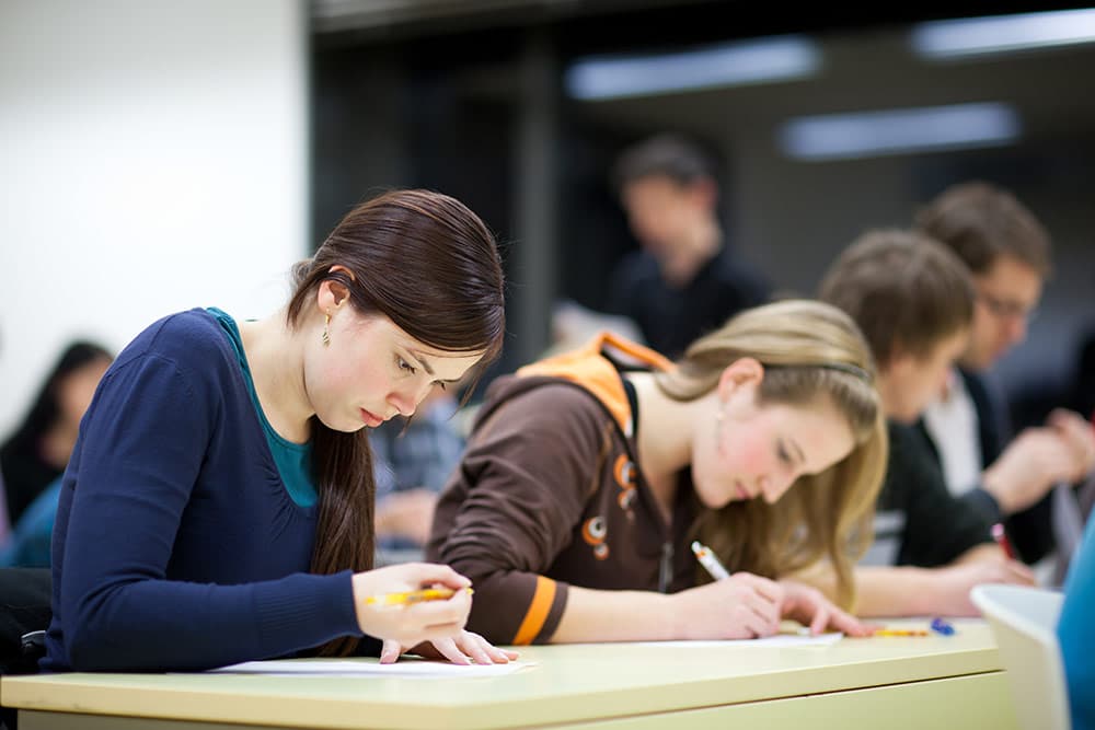 Étudiants concentrés pendant un examen du mastère Juriste d’entreprise.